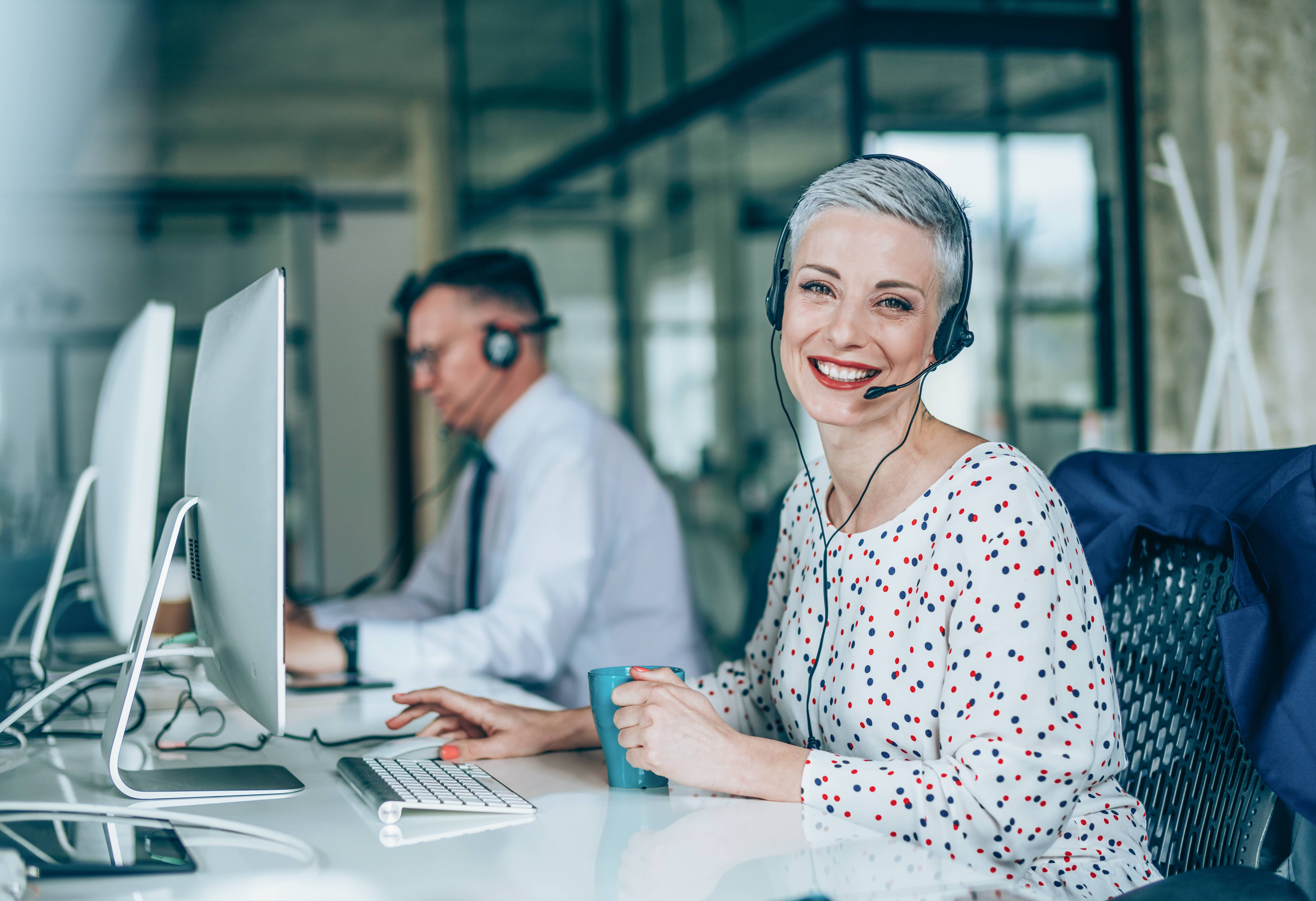 male and female energy brokers wearing headsets and working at computers 