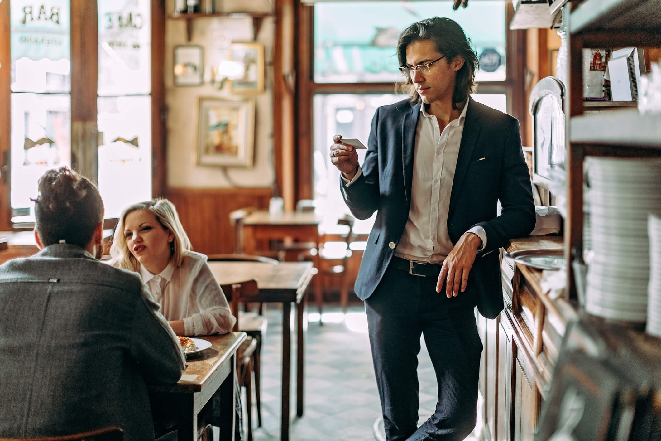 A man in a suit stands at the counter in a cafe examing the brand loyalty card he has been given