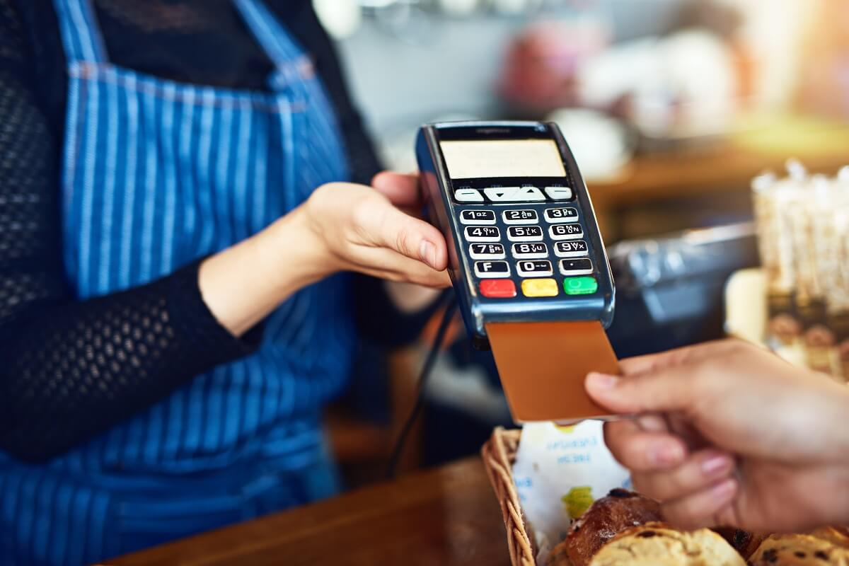 A shopkeeper holds out a card reader to a customer 