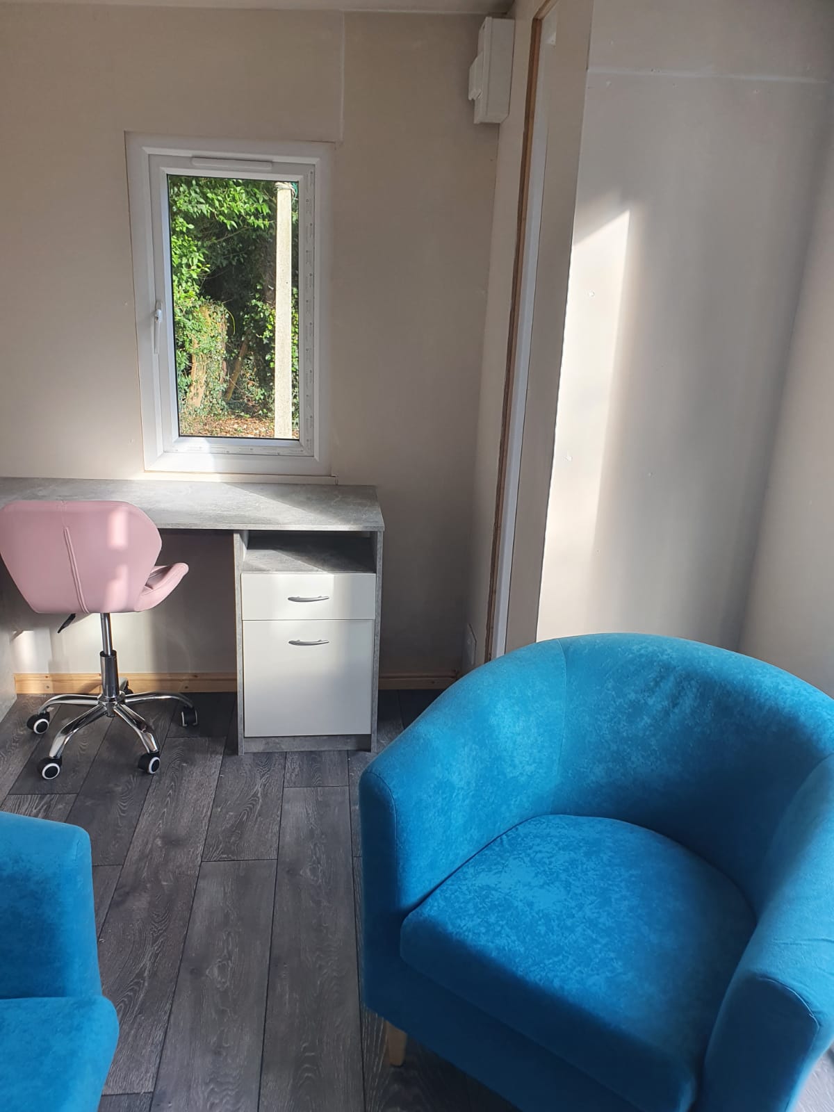 The inside view of the office, complete with two blue chairs and a desk