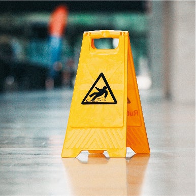 Yellow wet floor warning sign with image of slipping person in black triangle