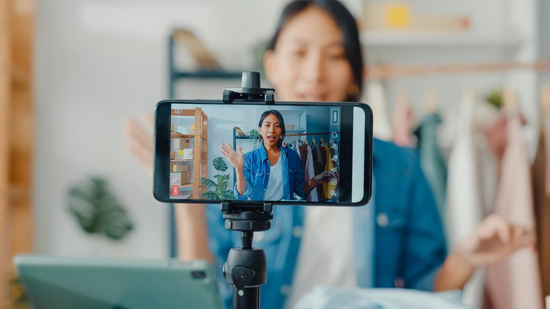 An influencer films herself on a smartphone to help market a small business
