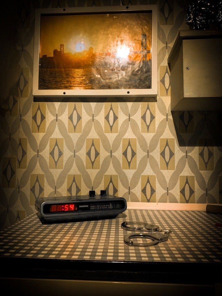 A closeup of an analogue alarm clock and some handcuffs in one of the rooms