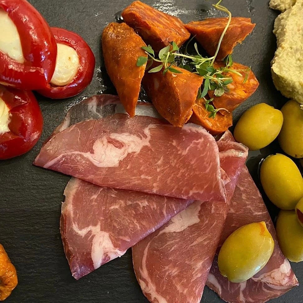 A board of cold meats and stuffed peppers