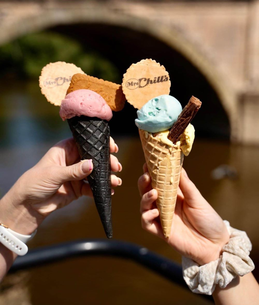 Two ice creams, one pink in a black cone and the other blue in a normal wafer cone 