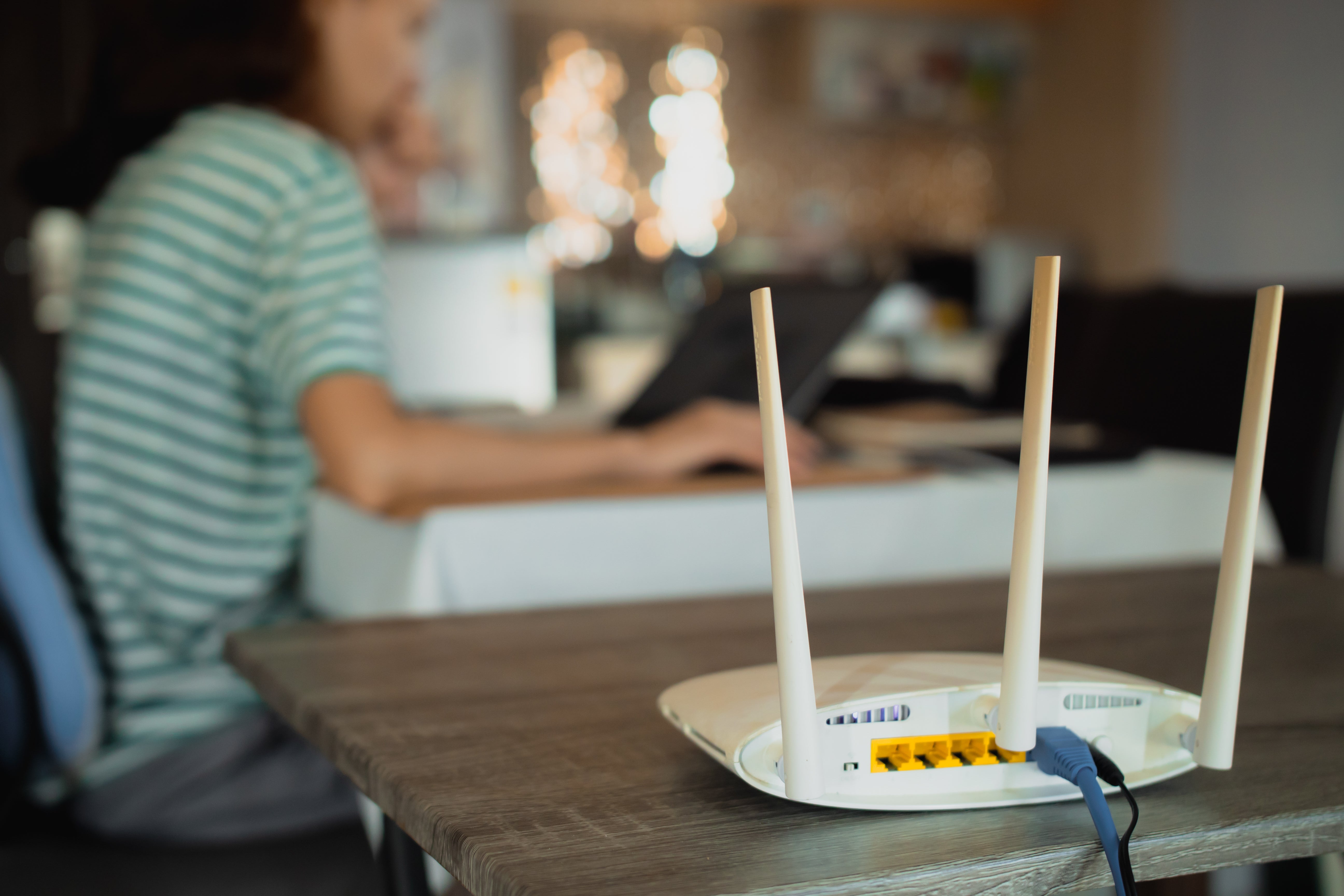 Someone works on a laptop connected to a router that uses FTTC broadband 