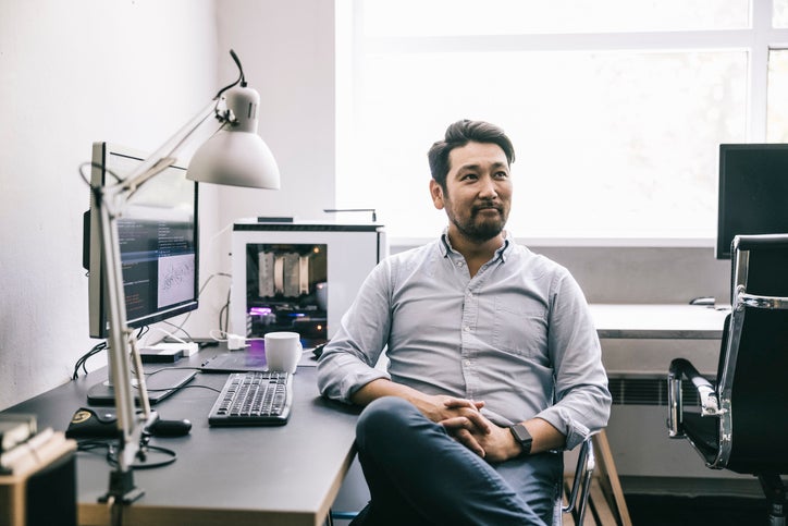 A small business owner sits in his office with his laptop and other IT systems