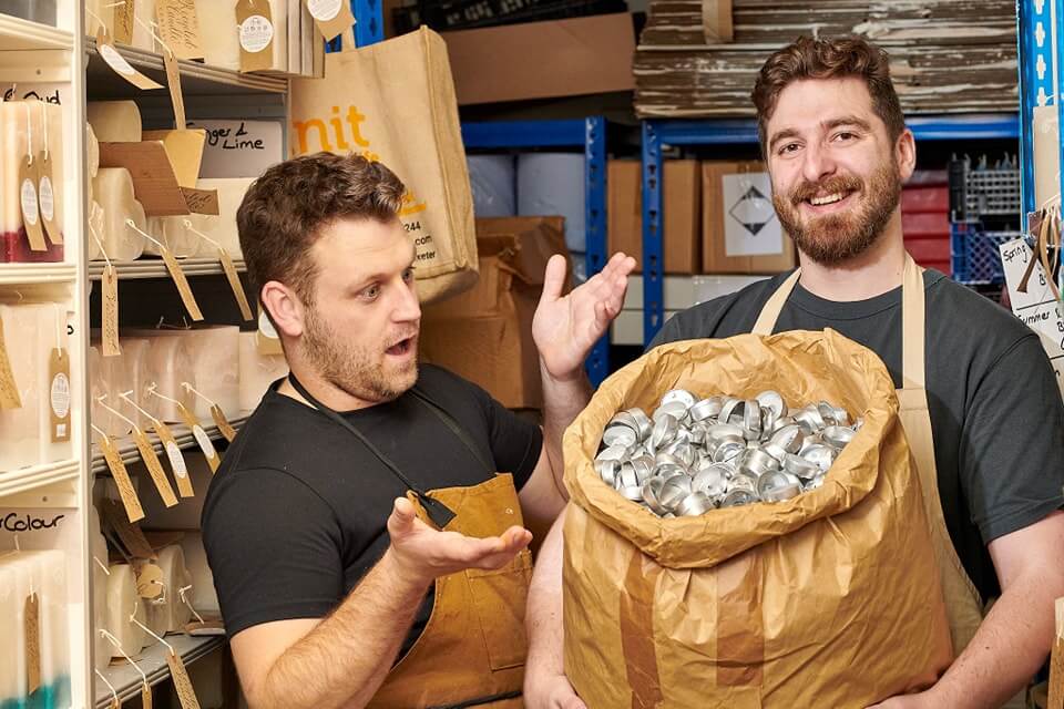 Business owners Richard and Sargon holding a bag of used tea light holders ready for recycling 