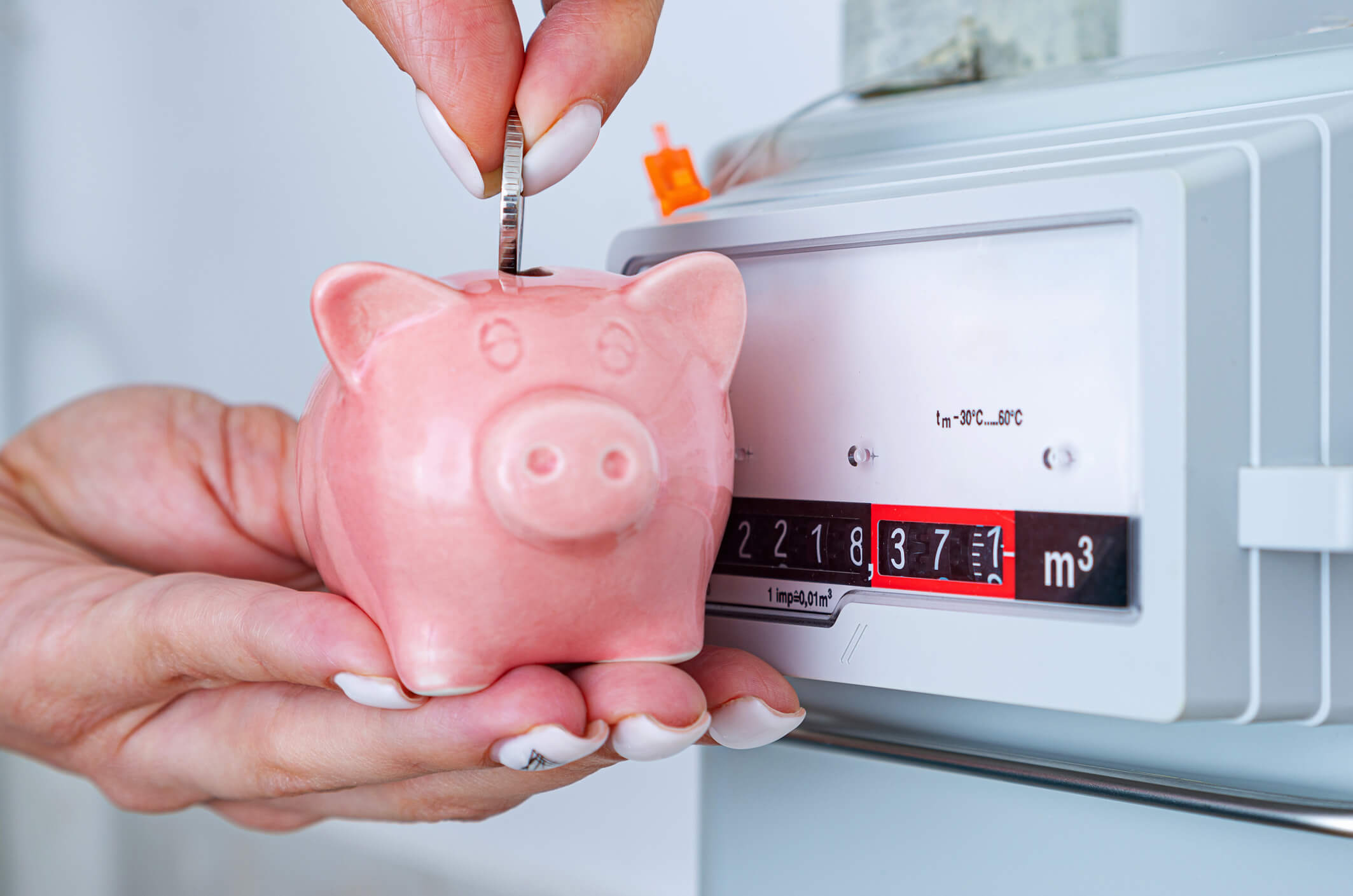 Woman's hand puts coin in piggy bank near a meter