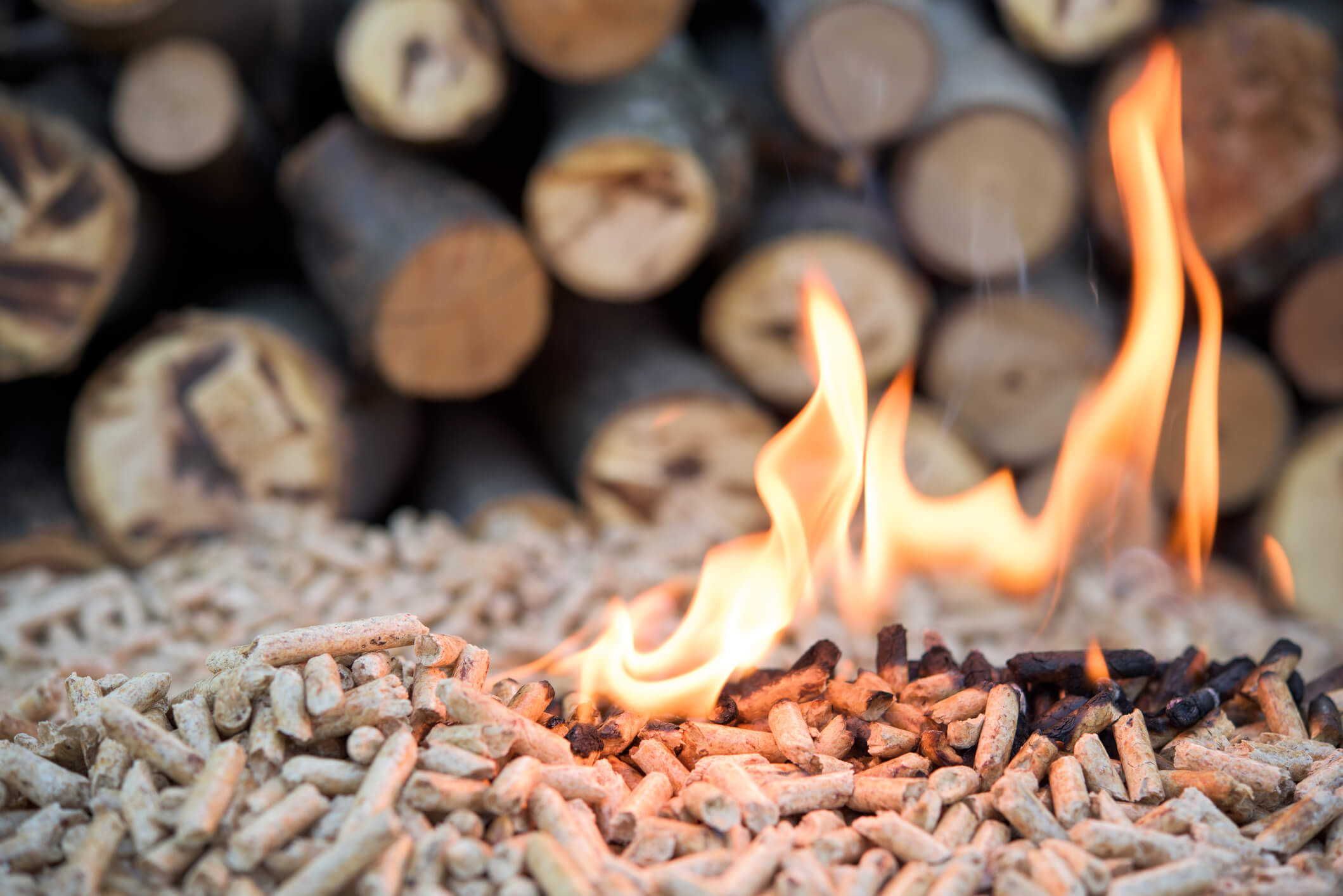 burning wood pellets in front of a pile of logs