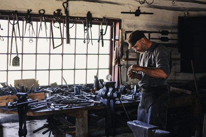 Tradesmen works among iron tools in workshop