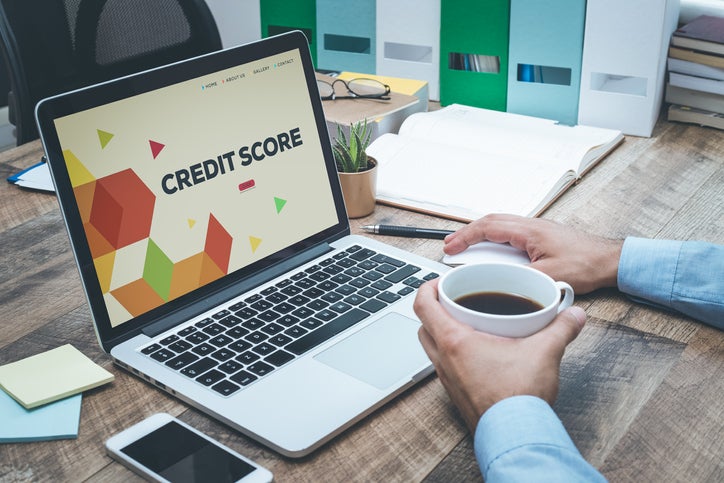 A business owner sits at his desk with a cup of coffee and checks on his laptop to see if he has a bad business credit score