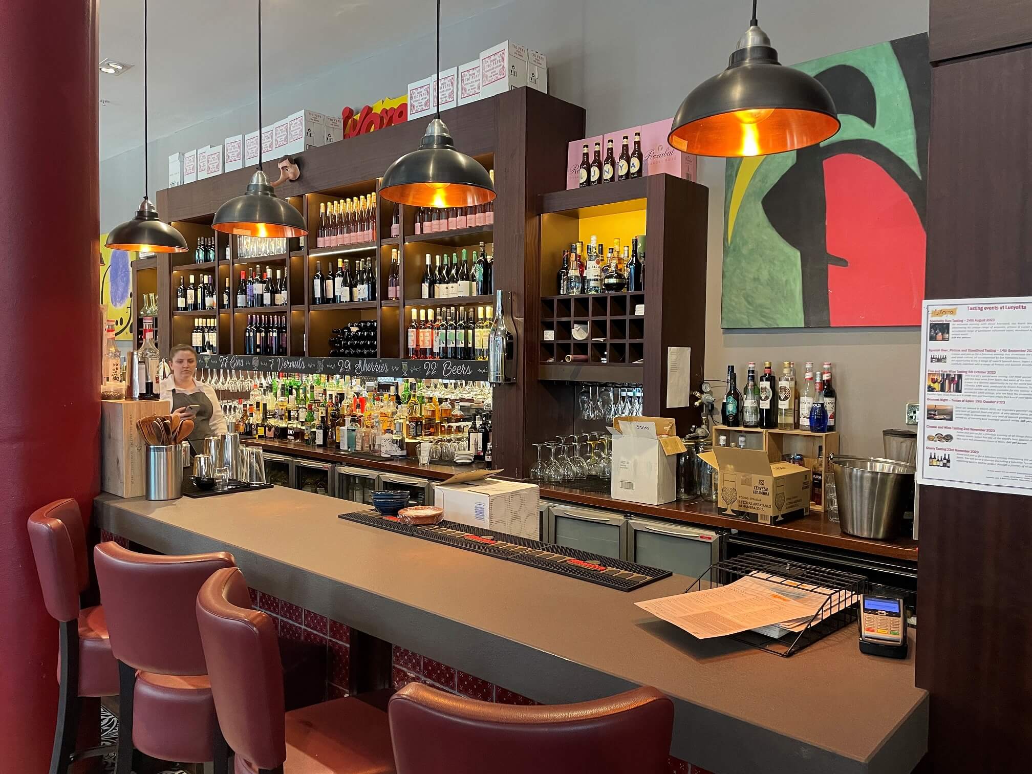 Interior of Lunya restaurant and deli, showing the bar area and a member of staff