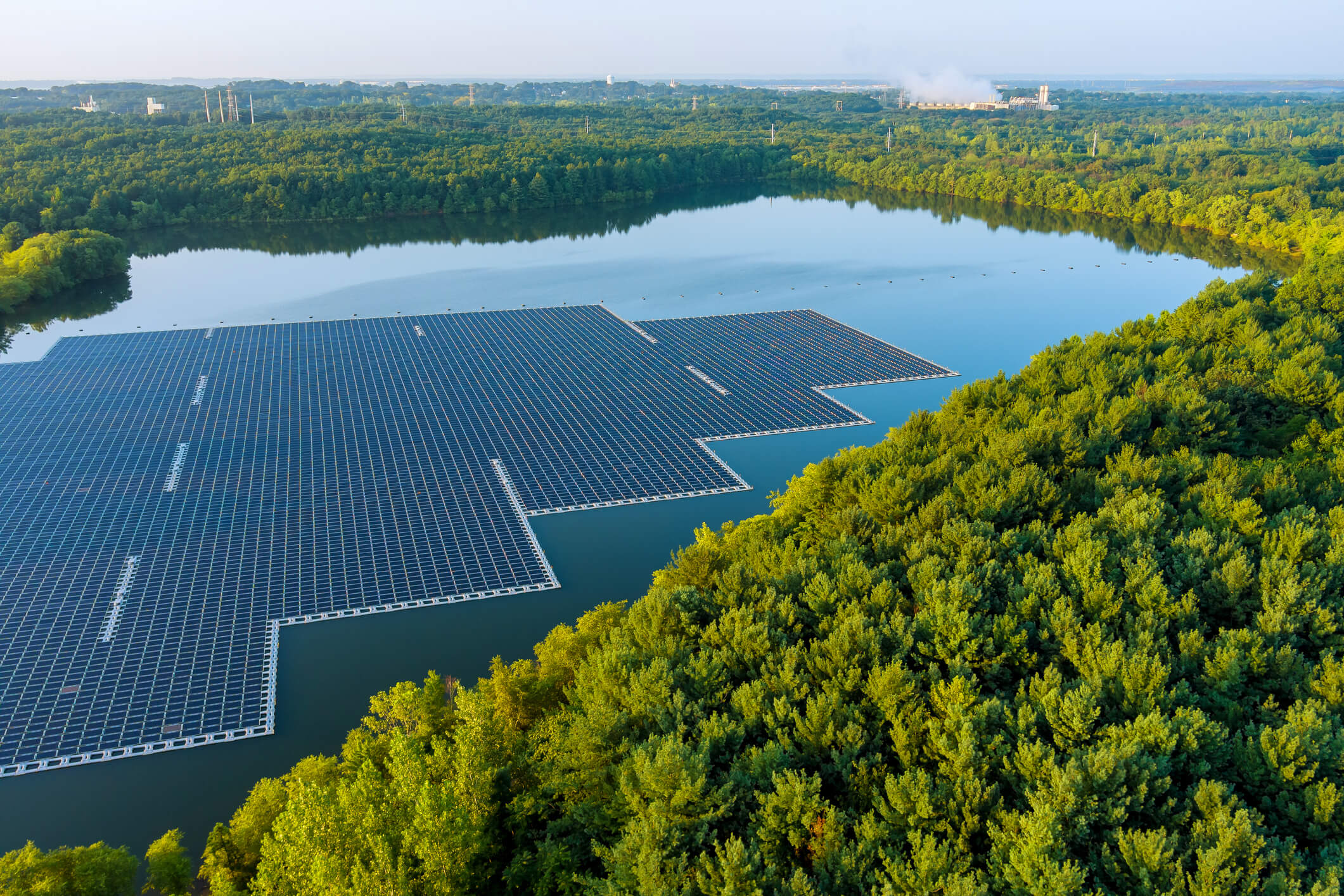floating solar panels placed on a lake surrounded by a forest 
