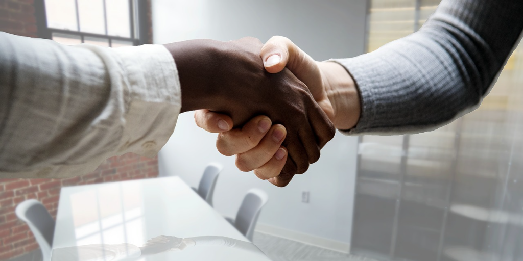 Two people shaking hands over an employment contract