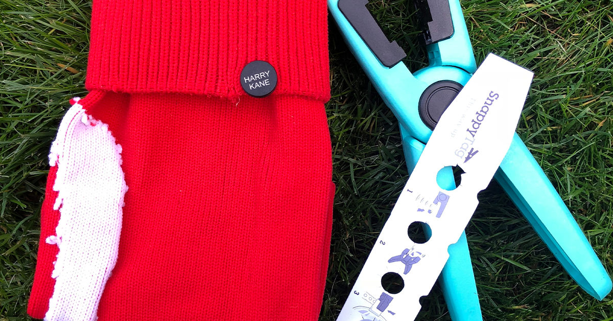 Red football sock  with black button attached with the name of HARRY KANE.