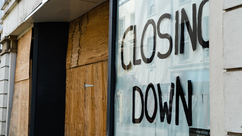 Closing down sign in a boarded-up shop window