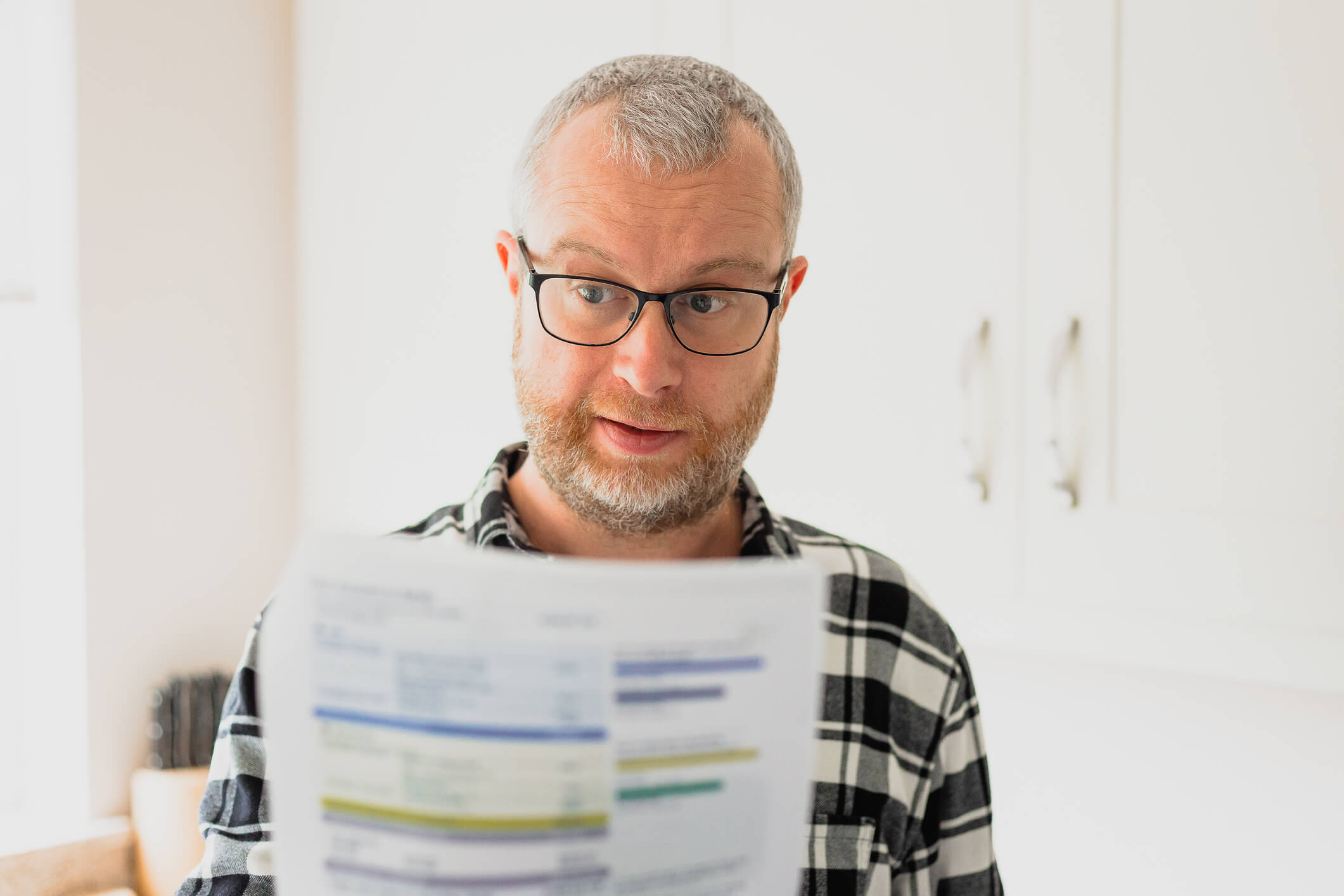 Male reading paperwork looking suprised that his insuranc premium has increased