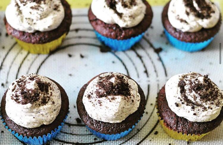 Six chocolate cupcakes with white icing and chocolate dusting