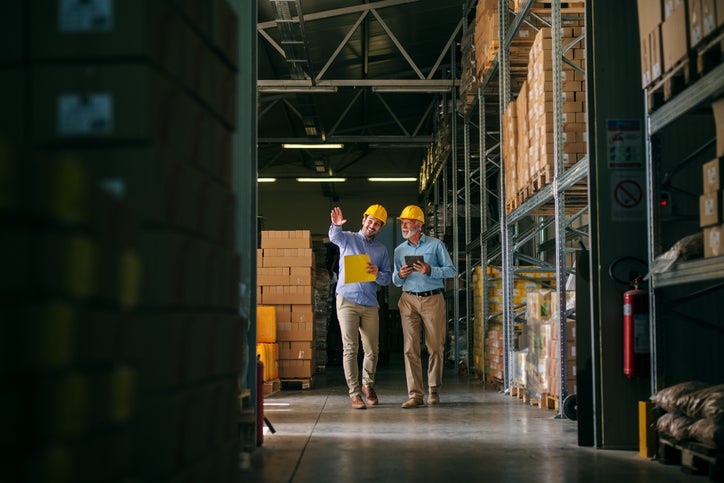 Two business owners walking through a warehouse checking their stock management system.
