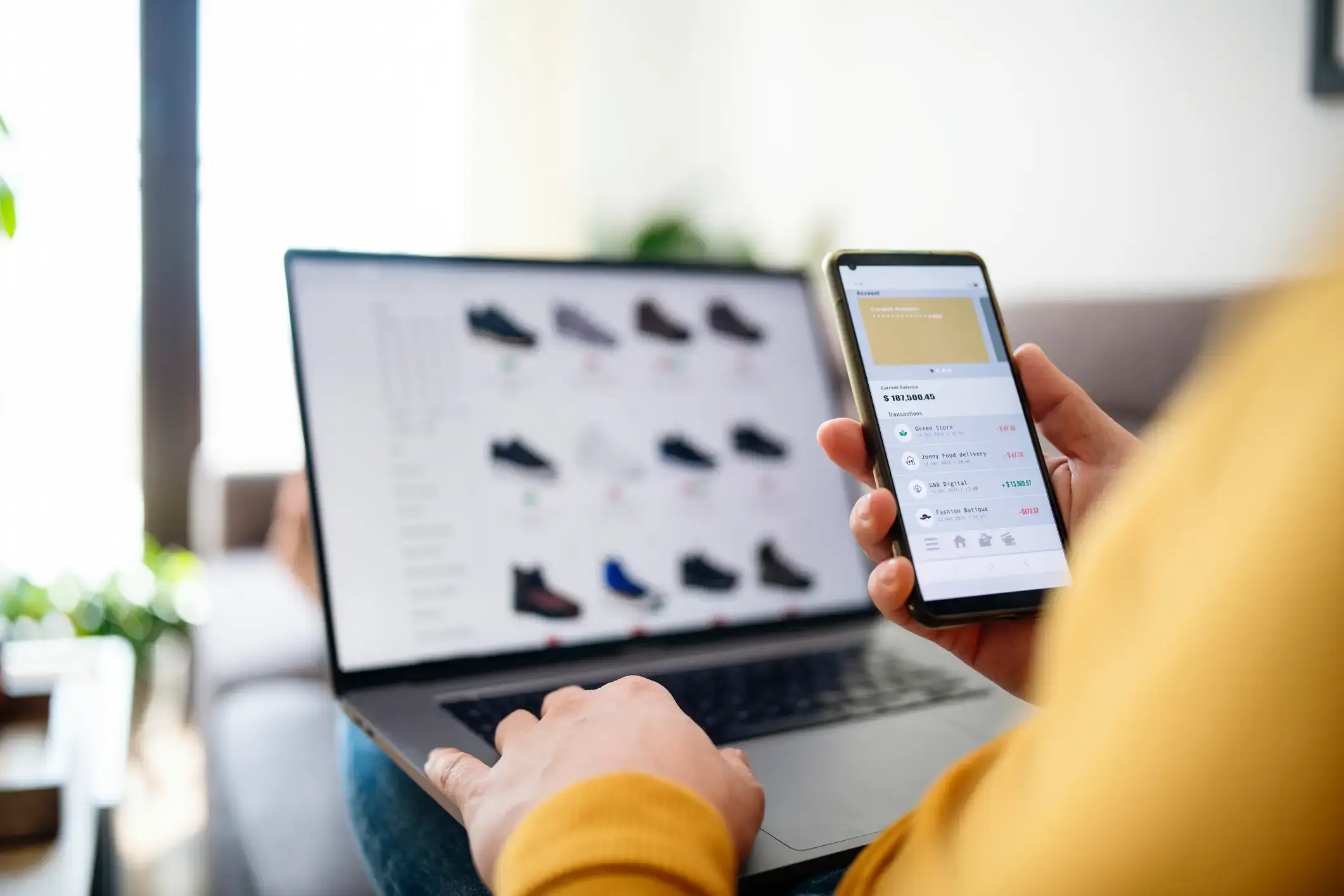 male using a laptop to browse shoes online and using a smartphone to check payment history