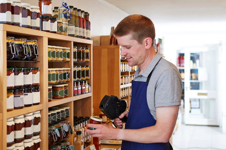 A business owner uses a price gun to put price labels on the products in his new shop