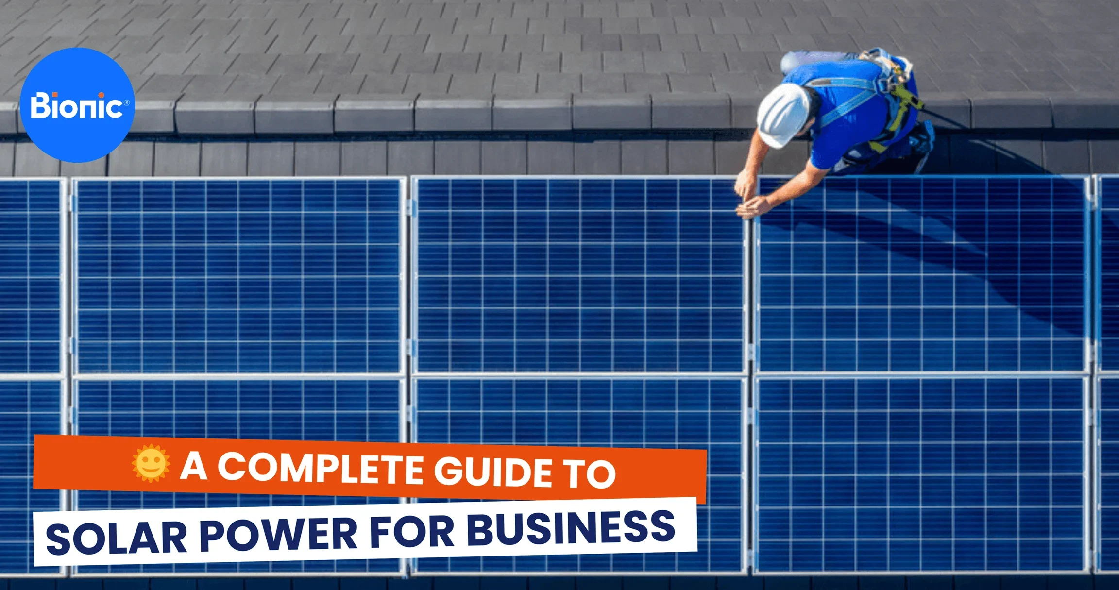Male engineer in blue suit and protective helmet installing photovoltaic panel system at a business property. Caption reads: A complete guide to solar power for business