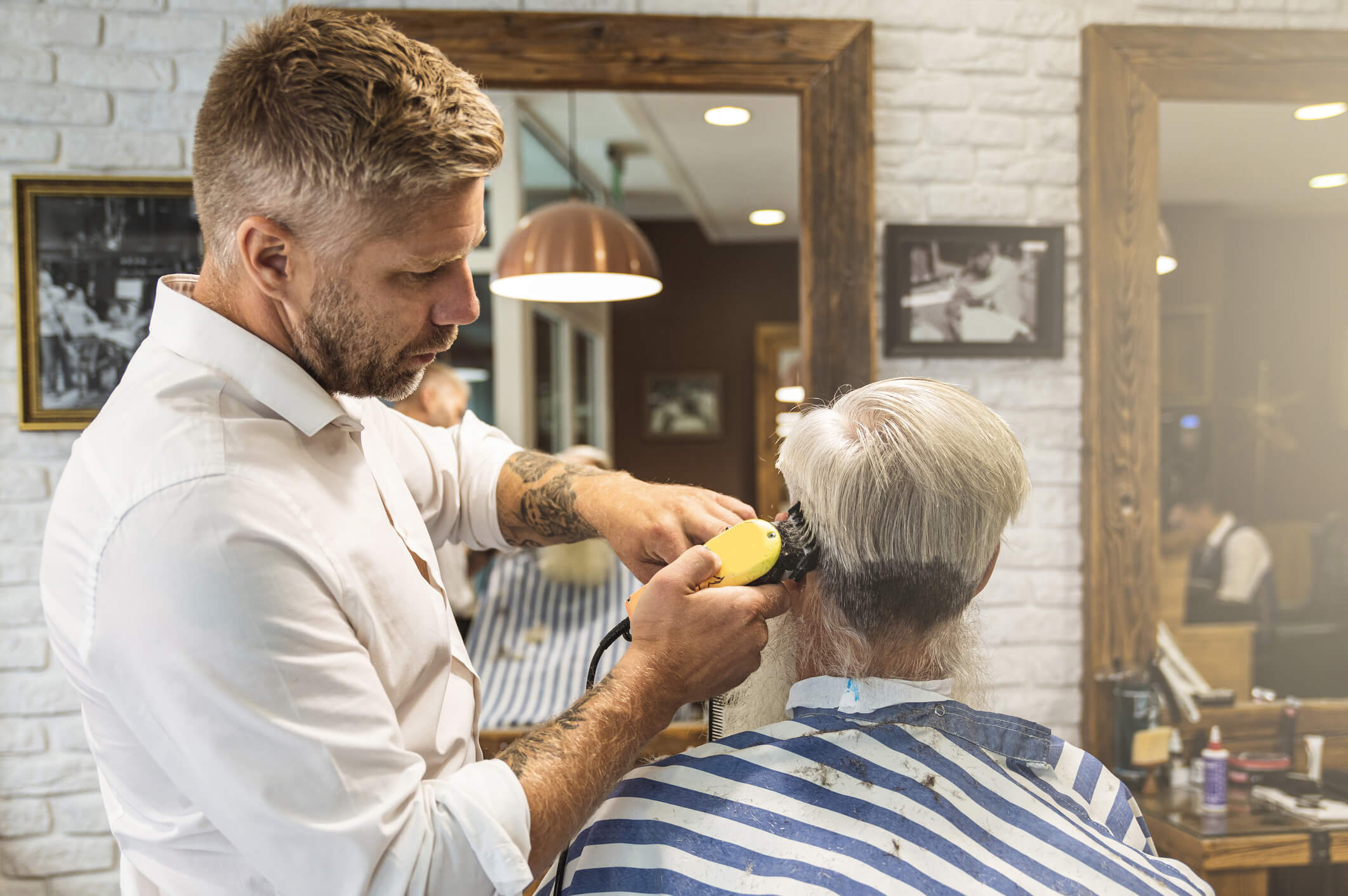 Hairdresser making stylish haircut for a man with grey hair in the barbershop