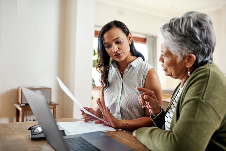 A small business owner sits with an employee near a laptop to talk throuhg their workplace pension