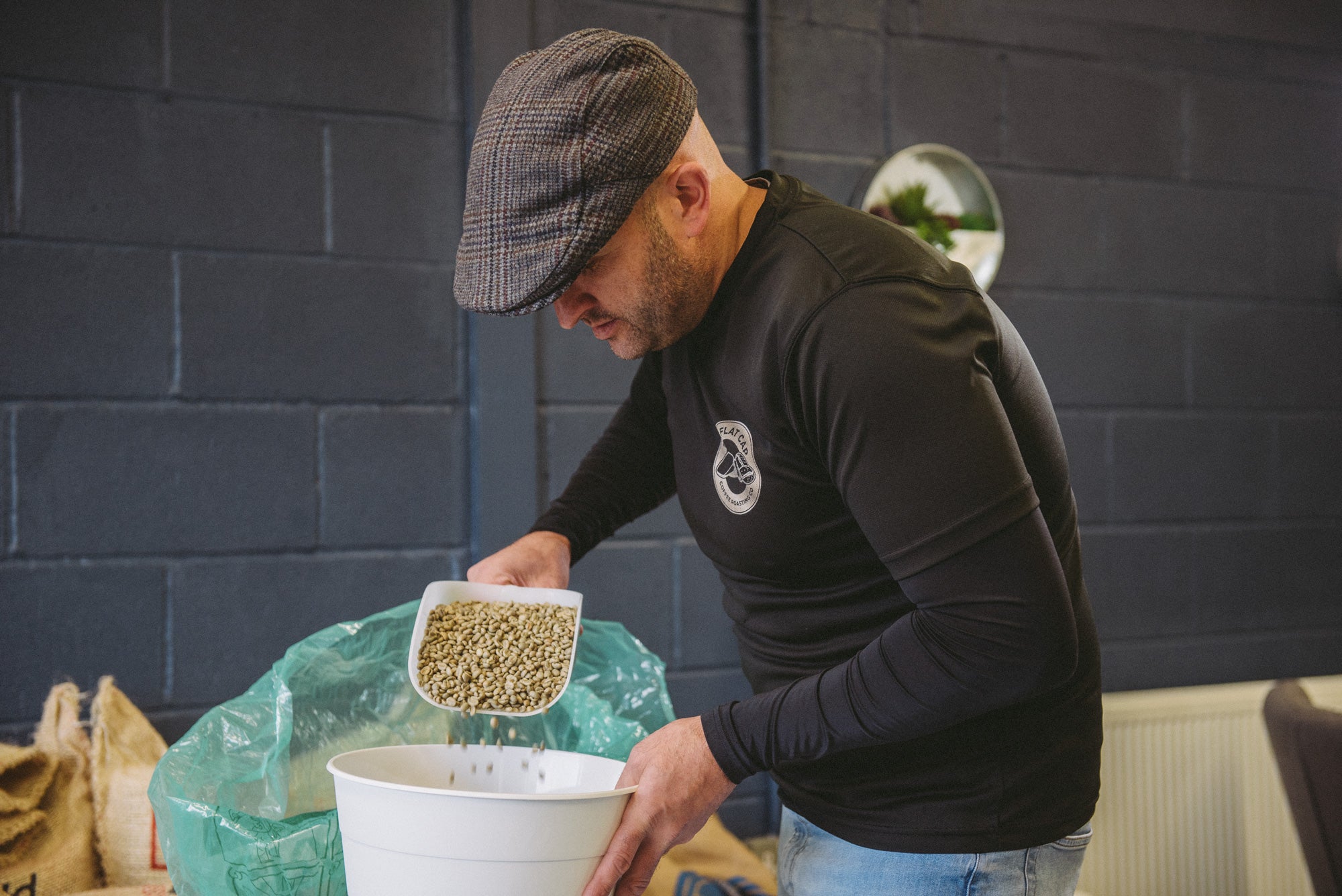 Mark of Flat Cap Coffee Roasting Co. pouring coffee beans into a drum