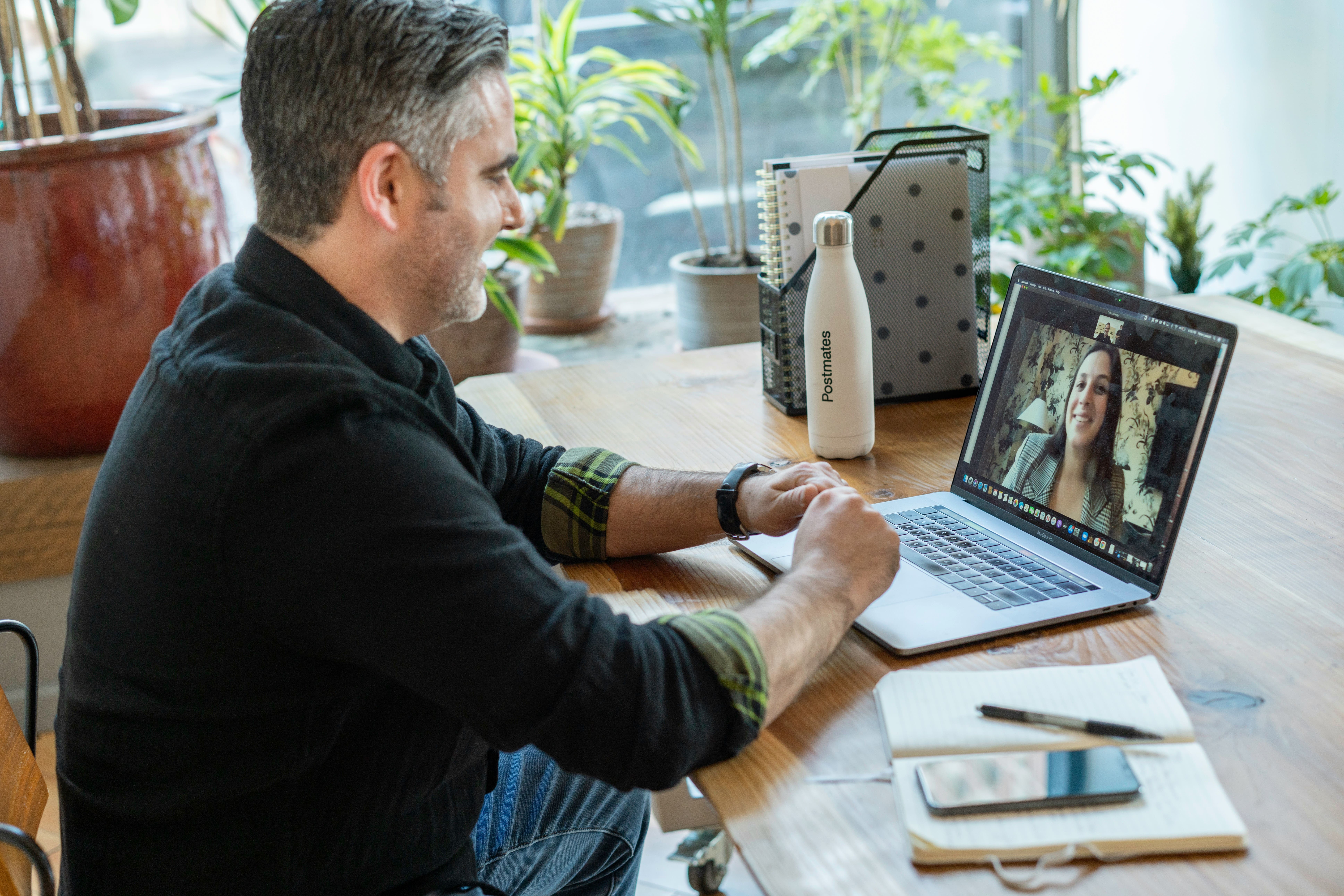 Man working from home on a desk with his laptop on a video call 