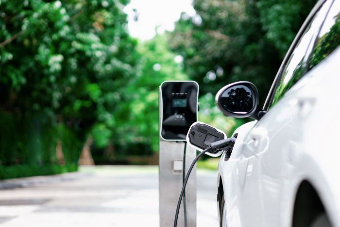 A white electric car charges at a public charging station