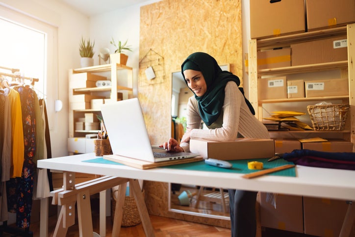 A micro business owner checks orders using her laptop while running her e-commerce small business from home.