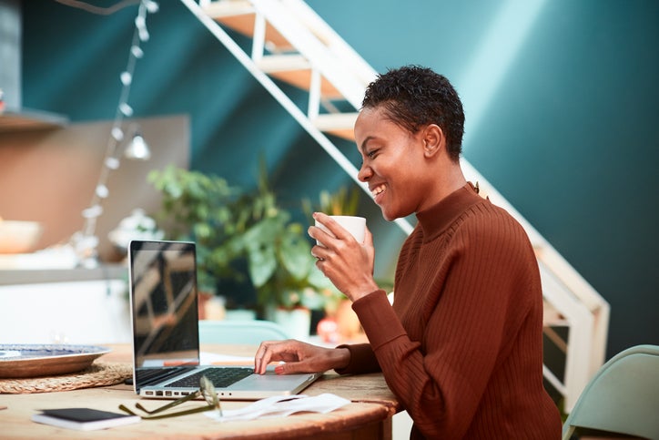 A small business owner smiles after completing her online tax returns on her laptop