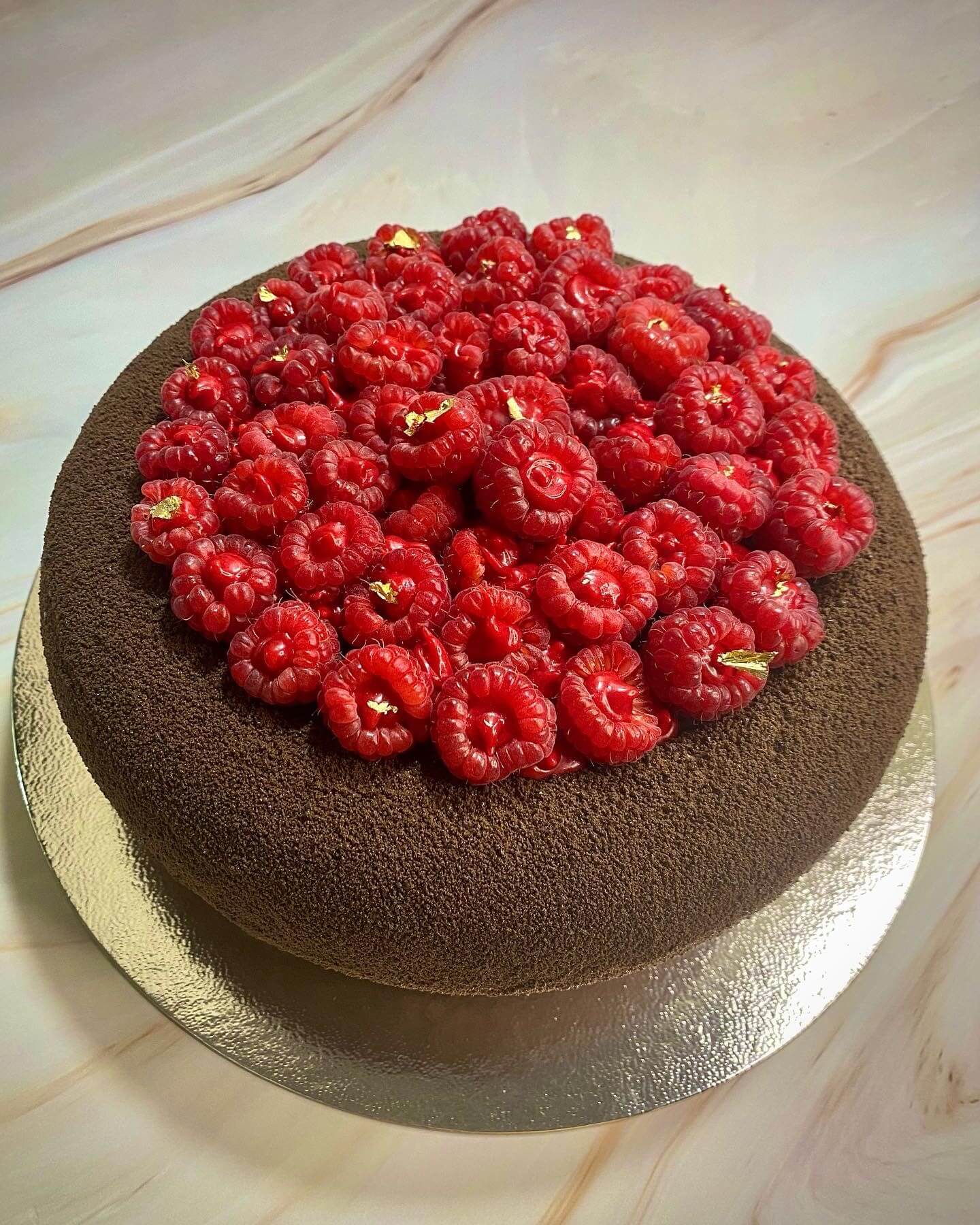 A chocolate cake topped with fresh raspberries.