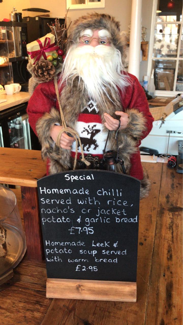 A Santa model holds a black slate menu which reads the specials of the day including homemade chilli and homemade leek and potato soup.