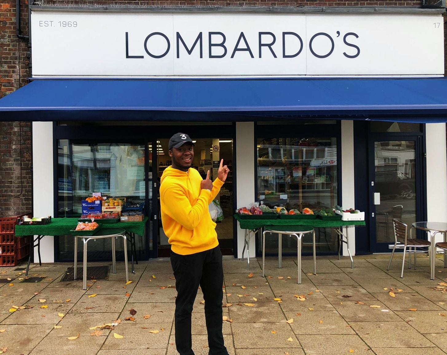 Bobby wearing a yellow hoodie and stood outside Lombardo's cafe