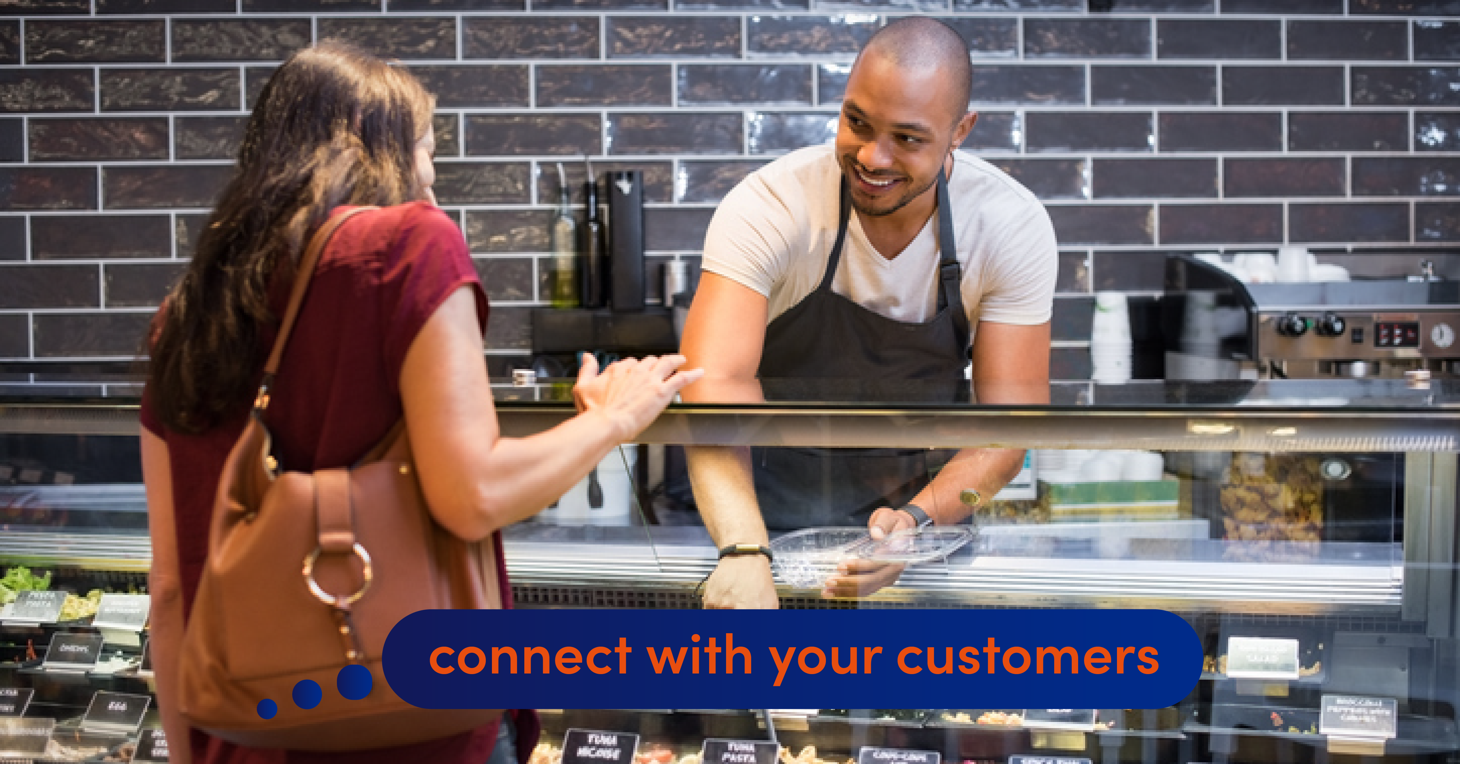 A deli owner picks out food from the counter for a customer