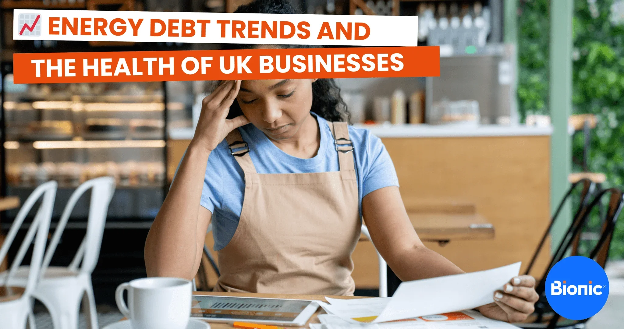 A business owner sits in her shop looking worried at her business energy bills and debt. The caption reads energy debt trend and the health of UK businesses