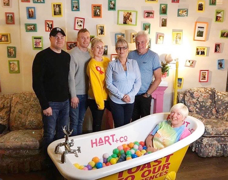 Five members of the HART restaurant team stand in front of a bathtub that has a sixth team member in.