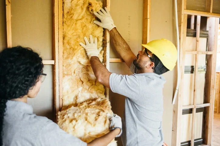 Two business owners fit insulation to the walls of their shop to save enery and save money