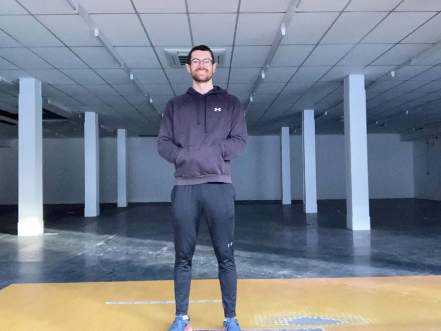 Chris stands in front of the empty gym space before the transformation 