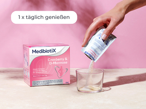 Medibiotix Cranberry & D-Mannose Packung neben einem Glas, in das der Inhalt des Sachtes ausgeleert wird.