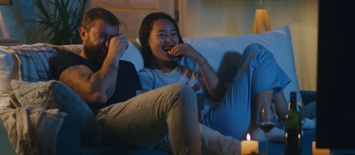 Pärchen sitzt auf der Couch und schaut einen Film.
