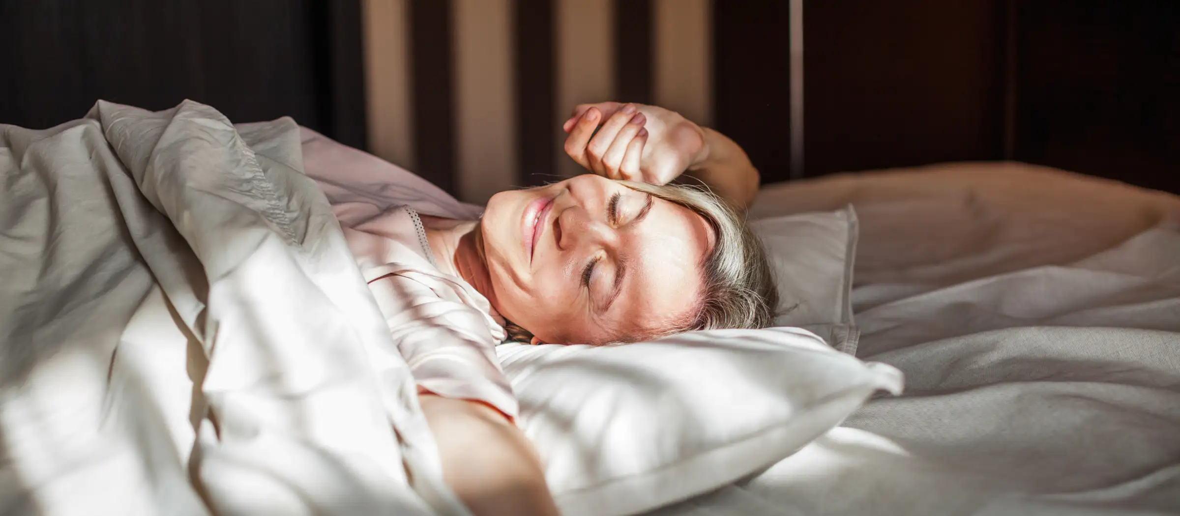 Frau räkelt sich zufrieden in einem Bett. 
