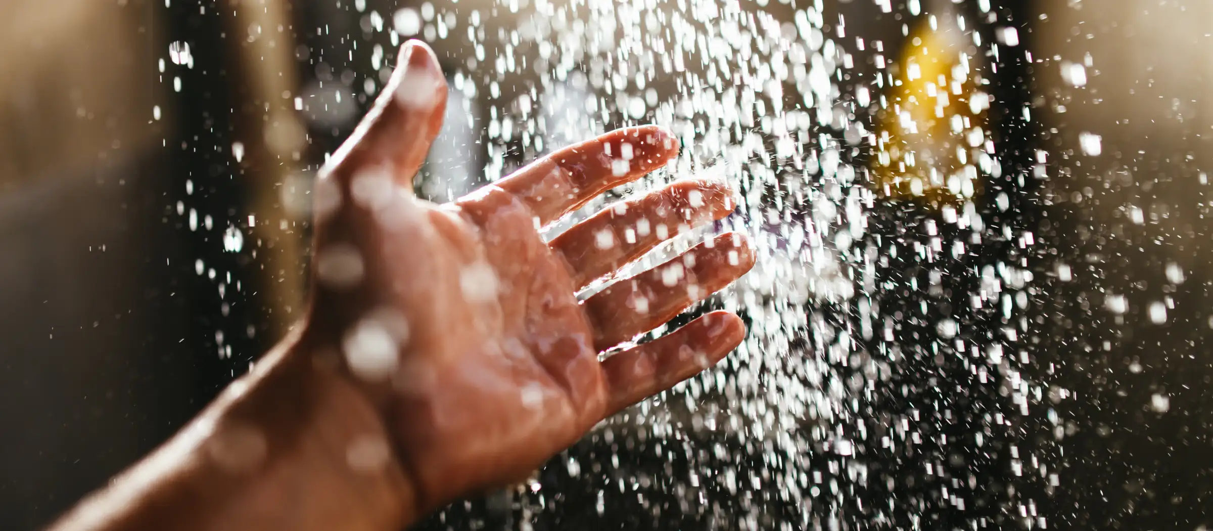 Hand wird unter einen Wasserstrahl gehalten. 