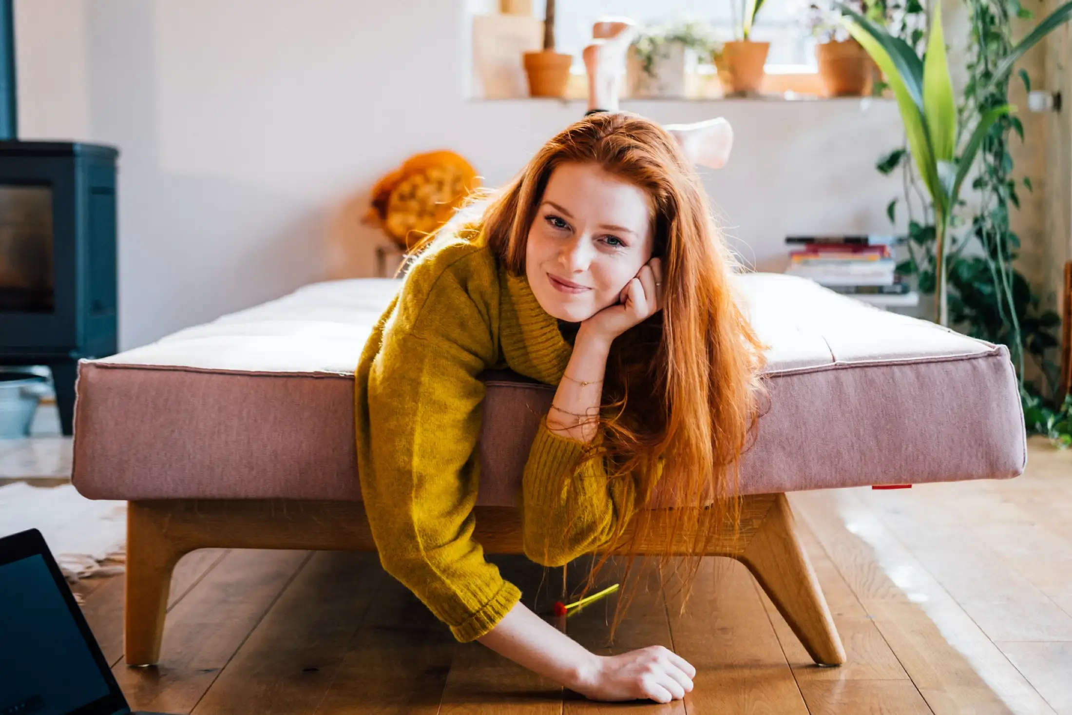 Frau liegt auf einem Sofa und lacht in die Kamera.
