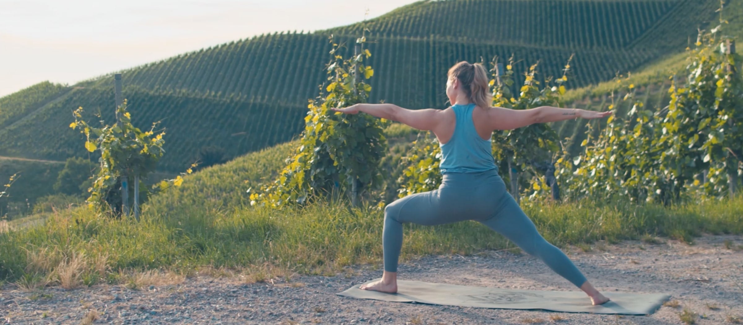 Frau zeigt Yogaübungen in den Weinbergen.
