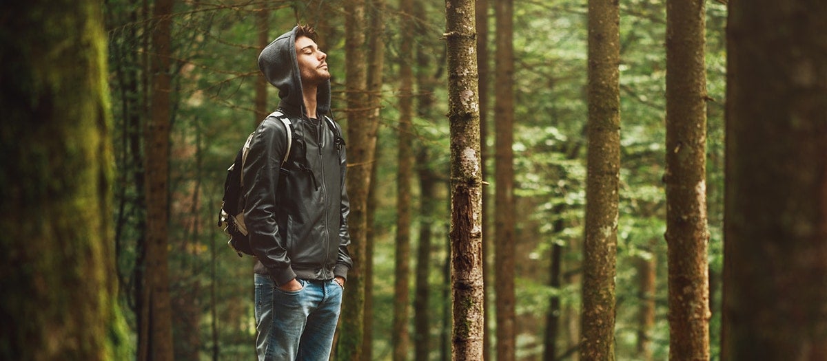 Mann steht auf einem Baumstamm im Wald.