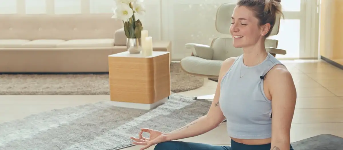 Frau mit geschlossenen Augen sitzt in Lotus-Pose.